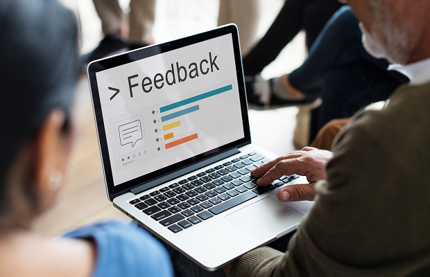 Feedback dashboard on a laptop screen being viewed by a small group in a meeting room.